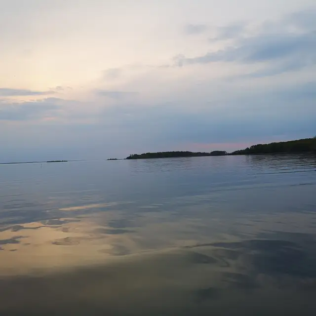 Calm lake at dusk with wooded shoreline